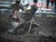 A motocross rider covered in mud.